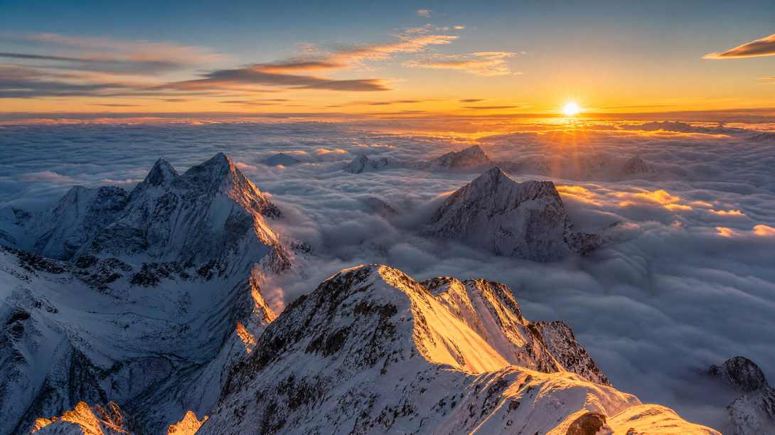 雪山之巅，云海翻涌，日出时分，金色阳光照在雪峰，壮观，广角 - 唯爱图库
